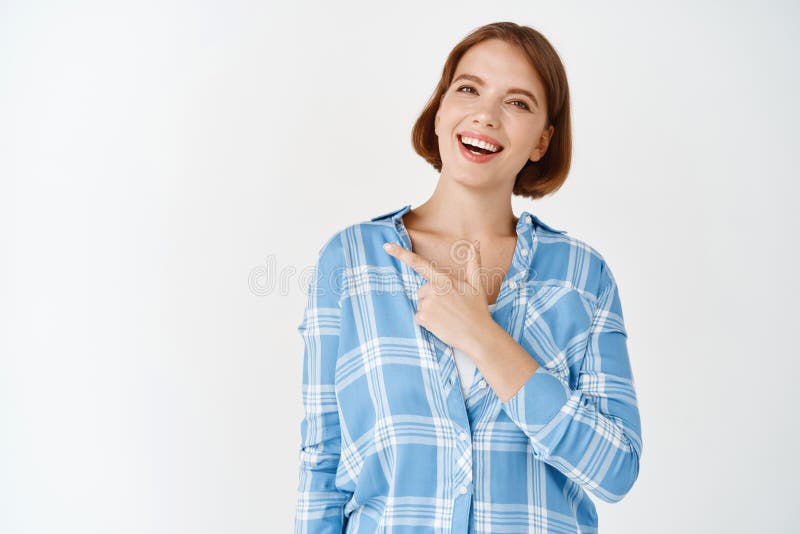 Portrait of beautiful woman smiling, showing logo on copy space. Girl pointing left at advertisement, standing in casual