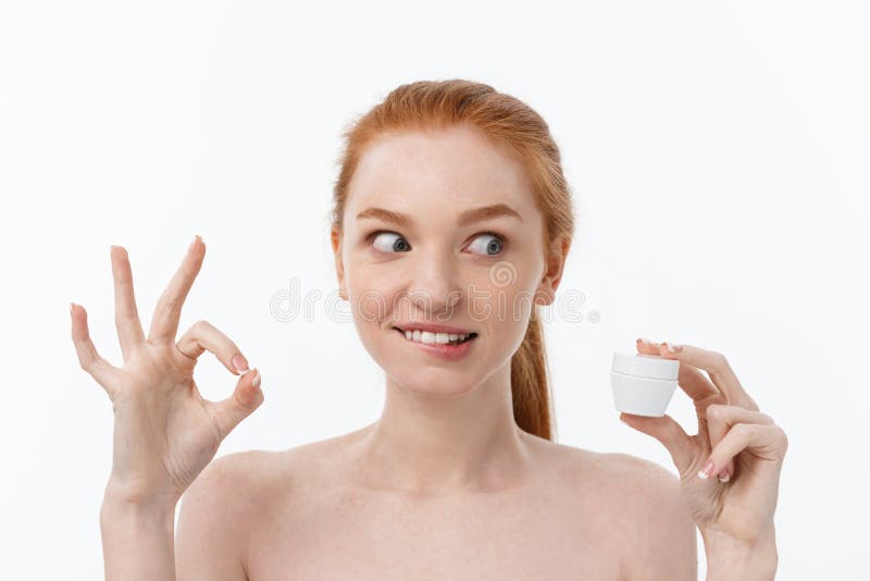 Portrait of beautiful woman smiling while taking some facial cream isolated on white background with copy space.