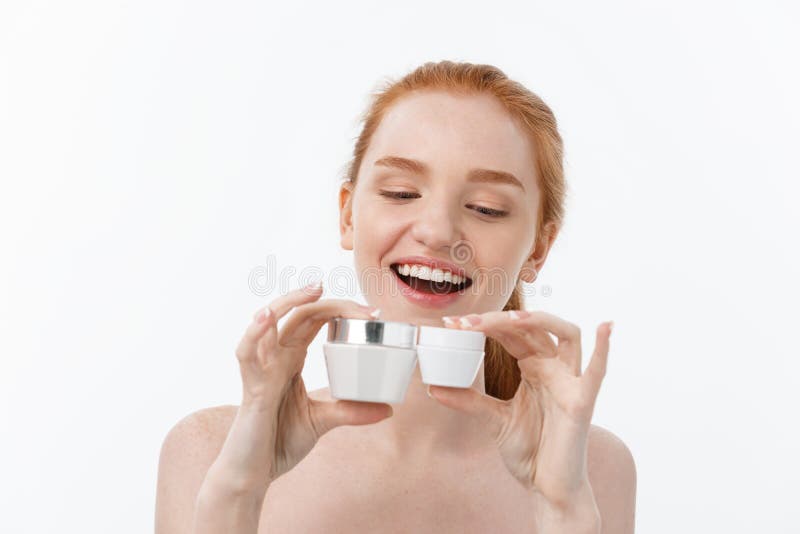 Portrait of beautiful woman smiling while taking some facial cream isolated on white background with copy space.