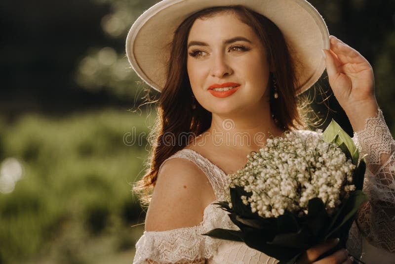 Portrait of a Beautiful Woman in a White Dress and a Hat with Lilies of ...