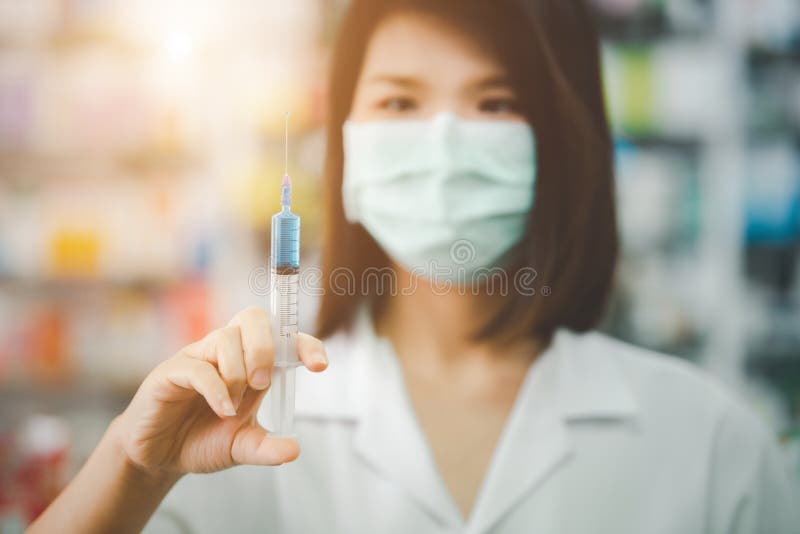 Portrait beautiful young asian doctor woman with face mask use vaccine syringe in hospital or clinic on blurred background