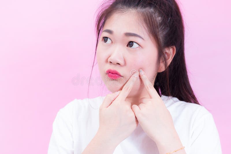 Portrait of beautiful Young Asian woman black hair wear a white t-shirt squeezing pimples on her face. Checks her skin, Skin care stock image Portrait of beautiful Young Asian woman black hair wear a white t-shirt squeezing pimples on her face. Checks her skin, Skin care stock image