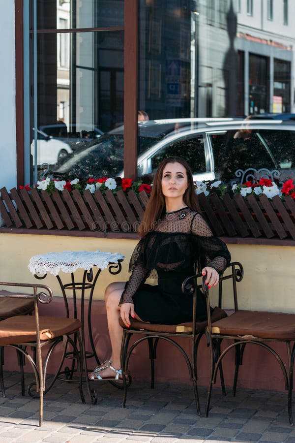 Portrait of a beautiful, young, attractive girl who sits on the street in a cafe. waiting for breakfast, summer, date. dream stock image Portrait of a beautiful, young, attractive girl who sits on the street in a cafe. waiting for breakfast, summer, date. dream stock image