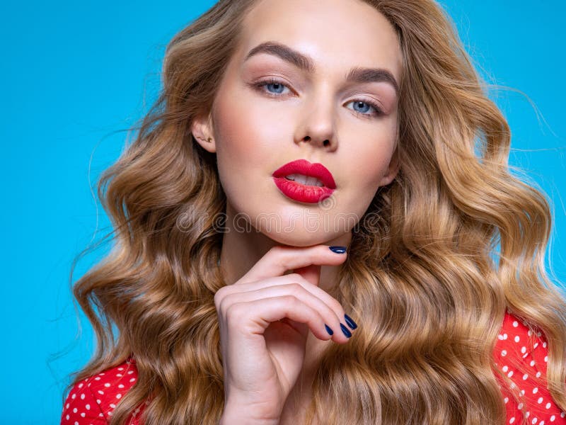 Portrait of a beautiful young blonde. Beautiful girl with long white hair. Face close-up of a sexy girl. Model in a red shirt poses in the Studio. Caucasian woman with red lipstick on her lips