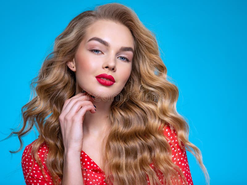 Portrait of a beautiful young blonde. Beautiful girl with long white hair. Face close-up of a sexy girl. Model in a red shirt poses in the Studio. Caucasian woman with red lipstick on her lips