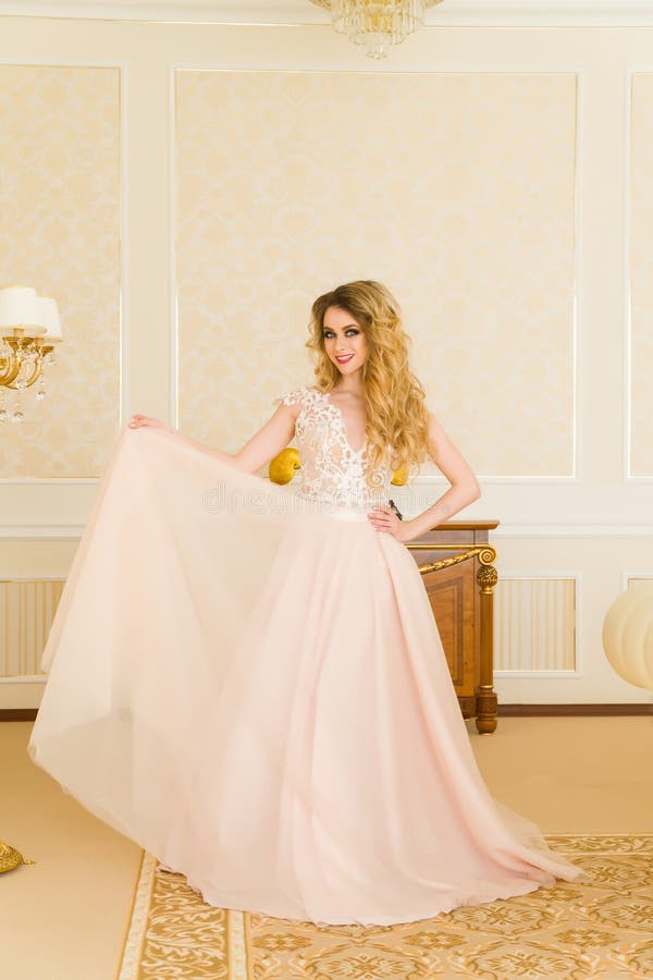 Portrait of beautiful young bride. A girl is posing in a hotel room. The lady is spinning in her wedding dress