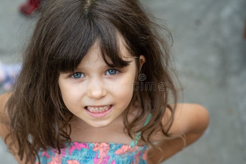 Portrait of a beautiful young brunette little girl, curly hair, blue eyes, wearing a summer dress