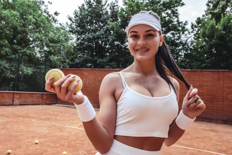 Portrait of a beautiful young girl with brunet hair and an excellent figure in sports clothes on a tennis court. young woman looking at the camera, active, adult, alluring, athlete, athletic, attractive, ball, beauty, body, cap, day, dress, fashion, fashionable, female, flirting, game, glamour, healthy, lifestyle, model, outdoor, play, player, pretty, seductive, sexy, short, skin, skirt, slim, sportswear, summer, sun, sunny, tanned, training, uniform, view, white