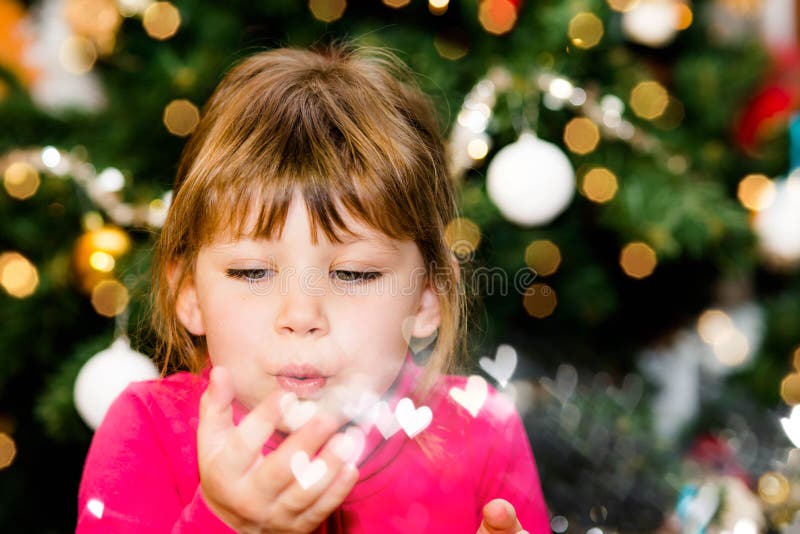 portrait of a beautiful young girl at the foot of the christmas tree sending love. portrait of a beautiful young girl at the foot of the christmas tree sending love