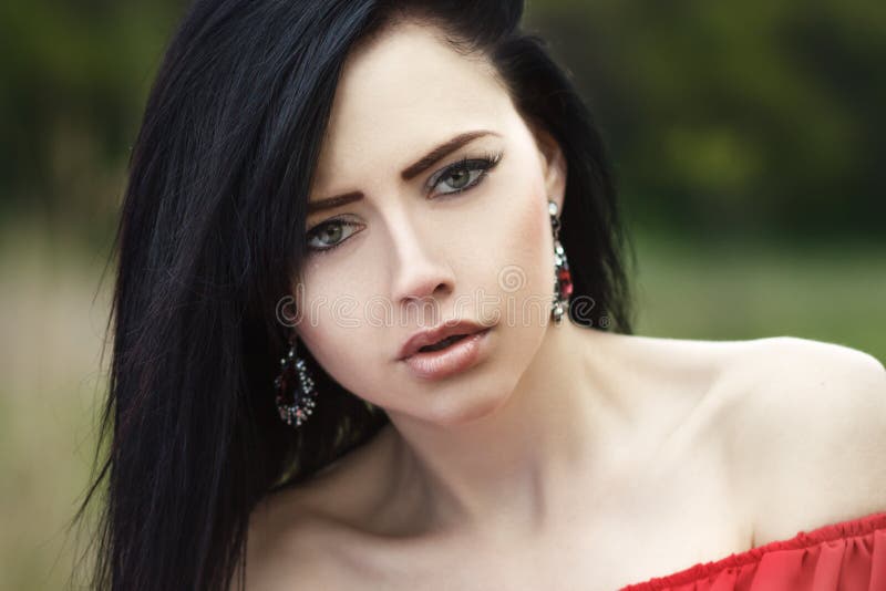 Portrait of a beautiful young girl with green eyes and bare shoulders, in a red dress on a green background summer nature stock images Portrait of a beautiful young girl with green eyes and bare shoulders, in a red dress on a green background summer nature stock images