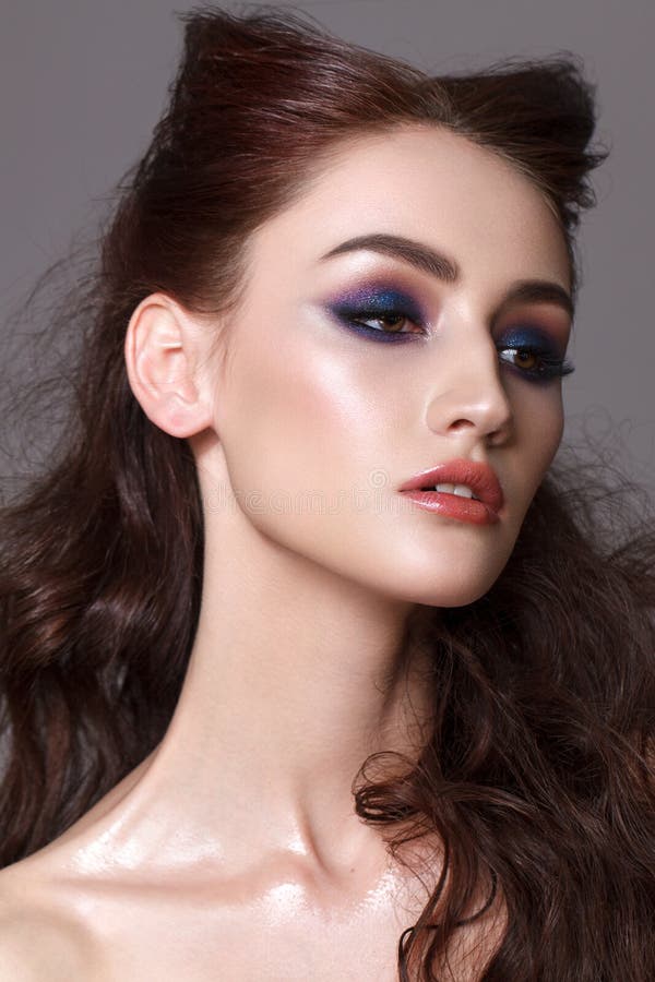 Portrait of a beautiful young model with professional makeup, trendy colorful smoky eyes and wavy hairdo