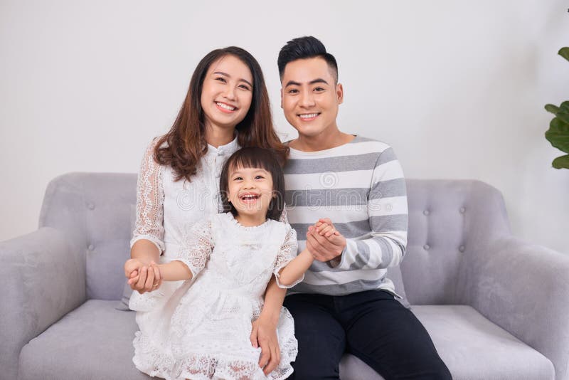 Portrait of beautiful young parents and their cute little daughter hugging, looking at camera and smiling royalty free stock photography Portrait of beautiful young parents and their cute little daughter hugging, looking at camera and smiling royalty free stock photography