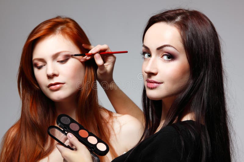 Portrait of beautiful young redheaded woman with esthetician making makeup stock photography Portrait of beautiful young redheaded woman with esthetician making makeup stock photography
