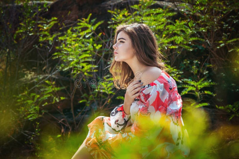 Portrait of serious brunette young woman, sitting in a forest