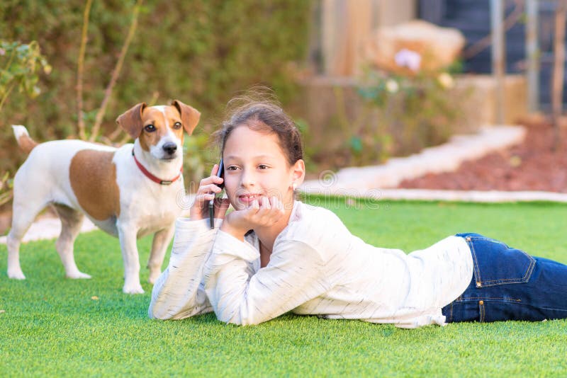 Portrait of beautiful young teenager girl with her dog using mobile phone outdoor. royalty free stock images Portrait of beautiful young teenager girl with her dog using mobile phone outdoor. royalty free stock images