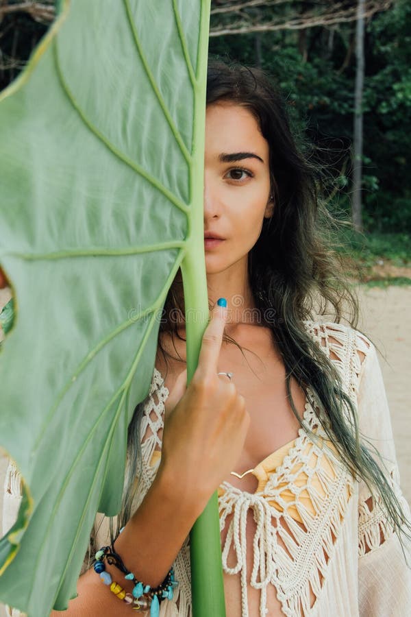 Portrait beautiful young woman against large green leaf tropical tree