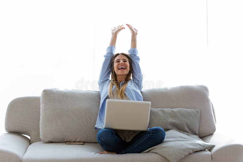 Beautiful young woman celebrating a succes while working with laptop at home.