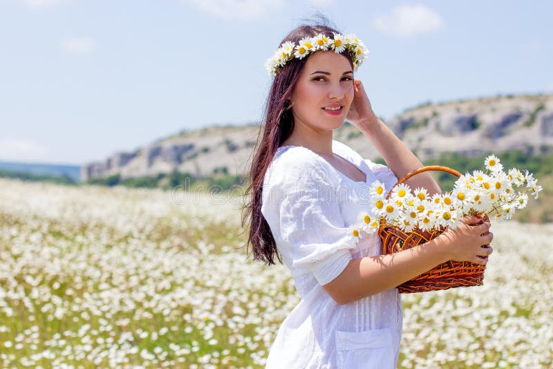 Portrait of a beautiful young woman in chamomile field. Happy girl collecting daisies. A girl resting in a field of chamomile. S