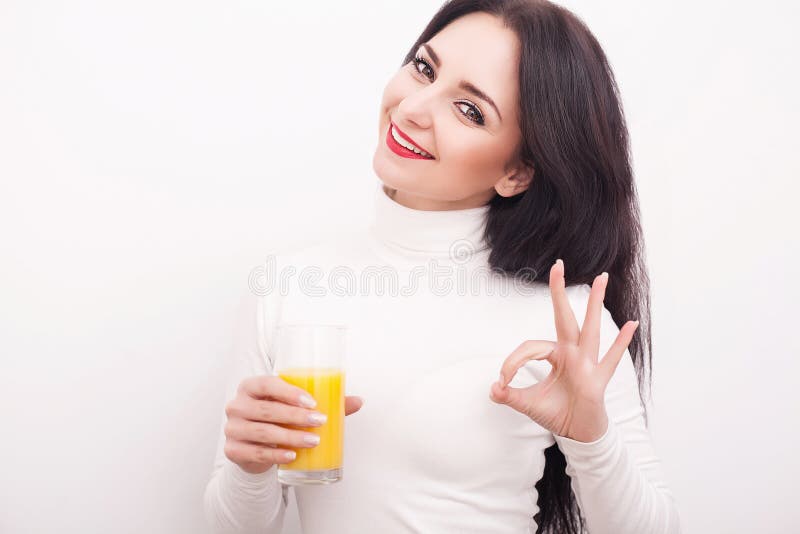 Portrait of a beautiful young woman with a glass of juice and orange, on white background