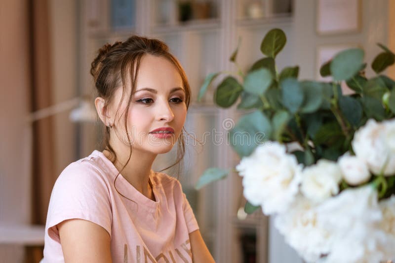 Portrait of a beautiful young woman at home, a vase of flowers