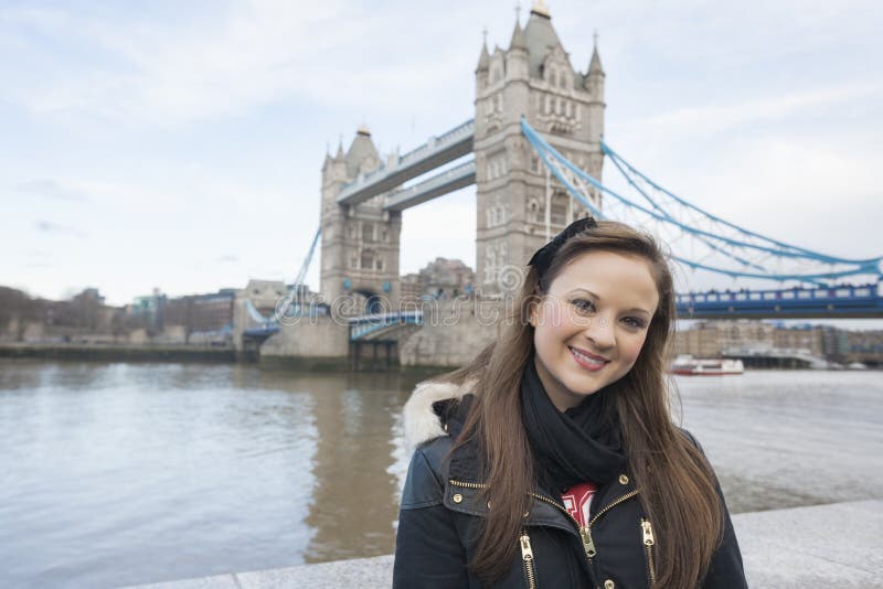 Portrait of beautiful young woman standing in front of tower bridge, London, UK stock photo Portrait of beautiful young woman standing in front of tower bridge, London, UK stock photo