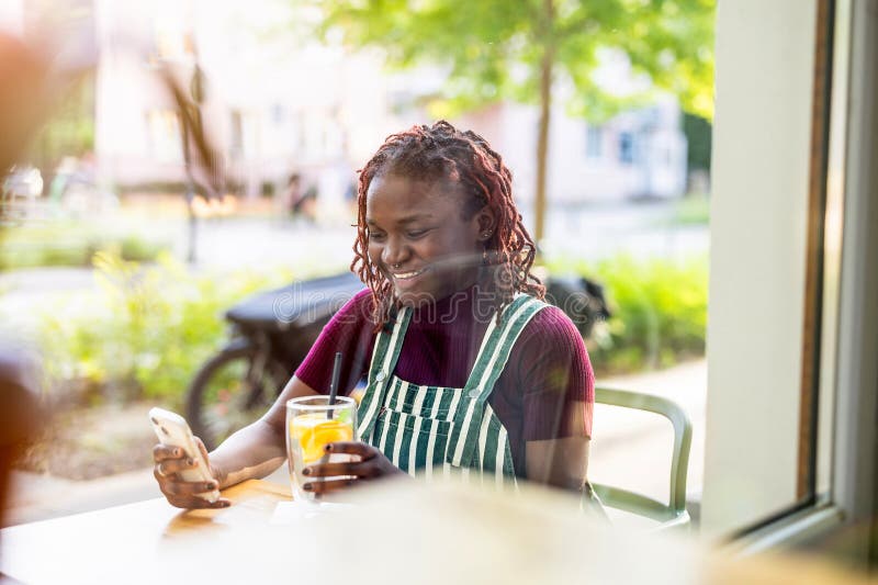 Black non-binary person sitting in an outdoor cafe royalty free stock images
