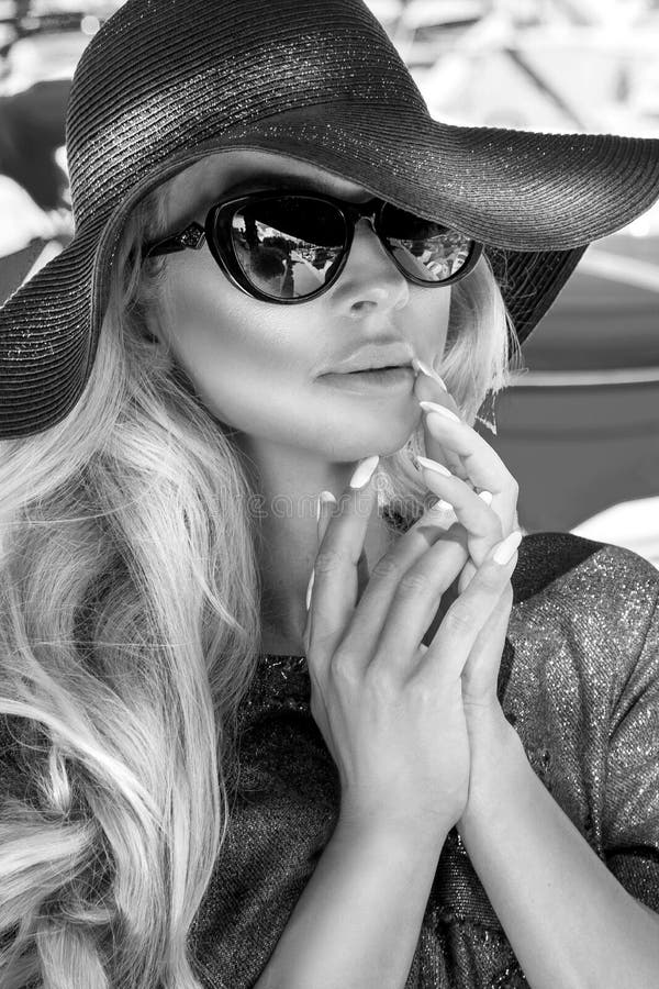 Portrait blanc du beau modèle blond sexy luxueux élégant noir utilisant un chapeau et des lunettes de soleil photographie stock libre de droits Portrait blanc du beau modèle blond sexy luxueux élégant noir utilisant un chapeau et des lunettes de soleil photographie stock libre de droits