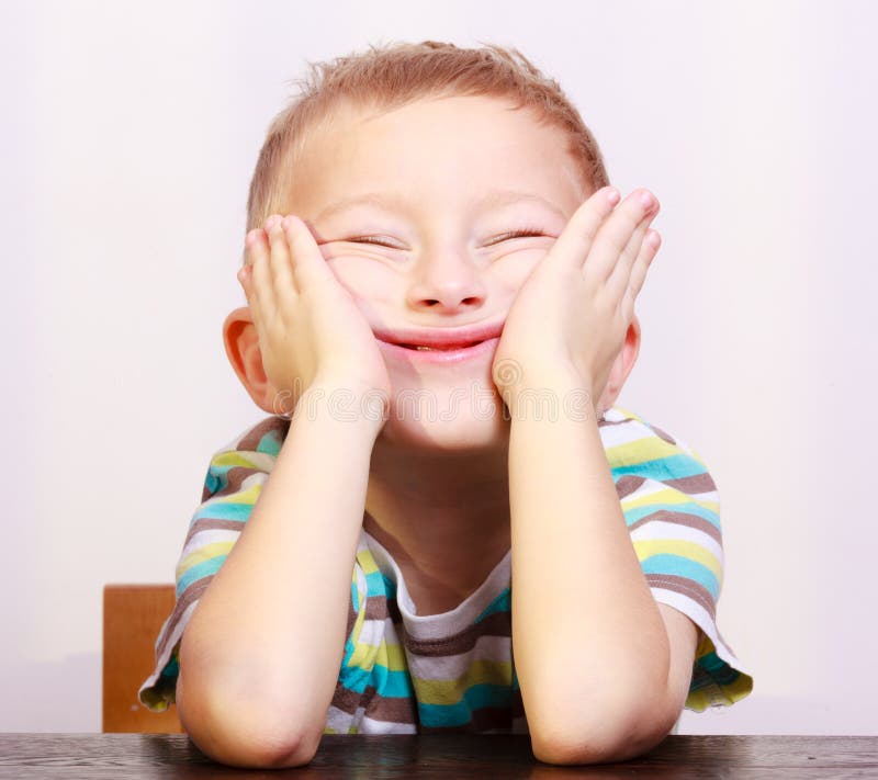 Portrait of blond boy child kid making funny face at the table stock photo Portrait of blond boy child kid making funny face at the table stock photo