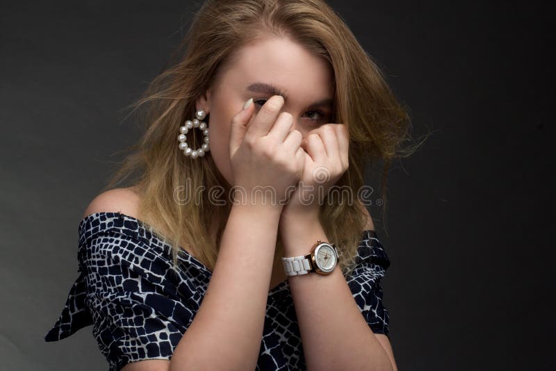 Portrait of blonde girl on a dark Studio background, he covers his face with his fists royalty free stock images Portrait of blonde girl on a dark Studio background, he covers his face with his fists royalty free stock images