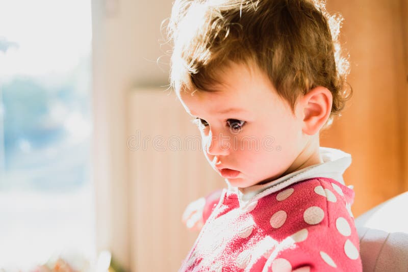 Portrait of Bored and Thoughtful Baby in a Bright Room Stock Photo