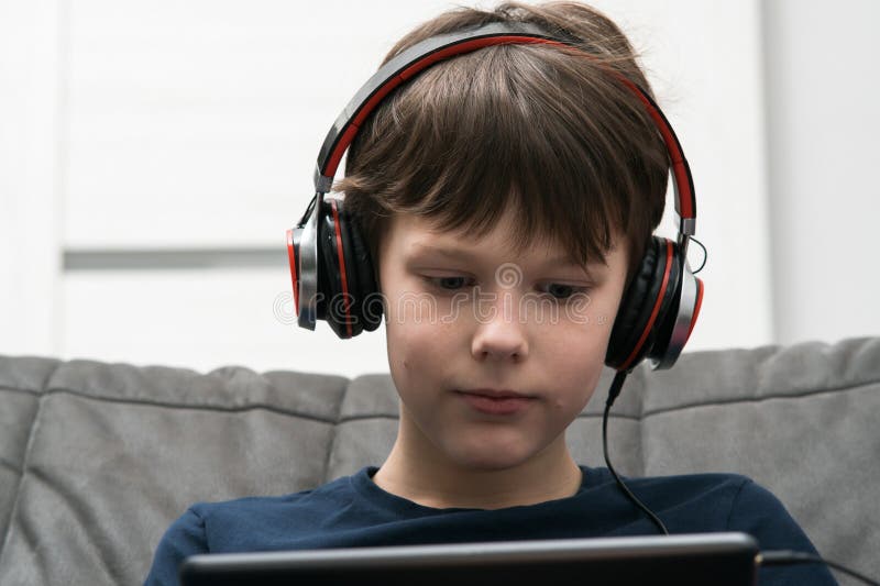 Portrait of boy with digital tablet computer. Child in wired headphones play videogame on gadget or listen to music.