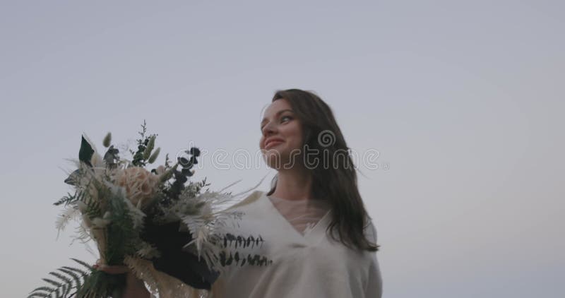 bride in white wedding stylish dress holding bouquets of flowers