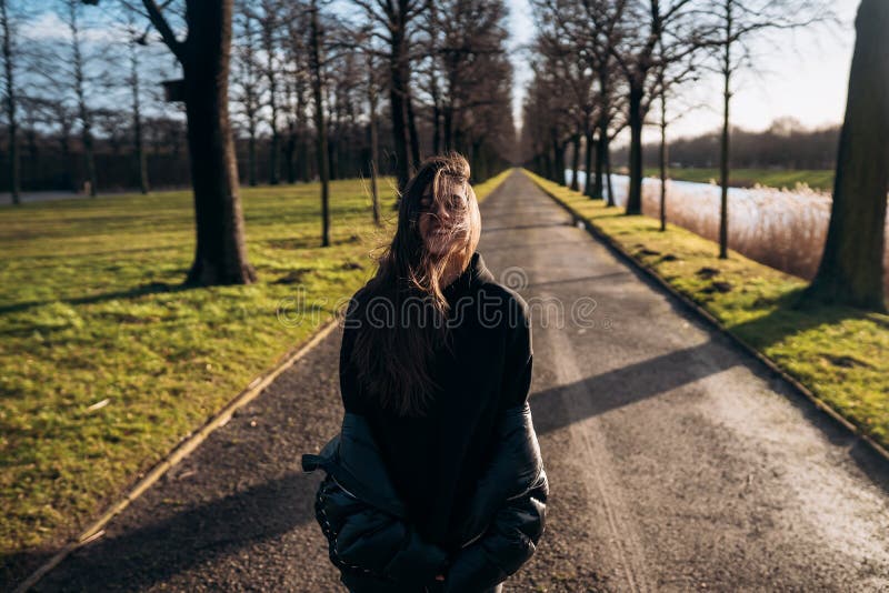 Portrait of a brunette girl having fun in a park in the rays of the bright sun.