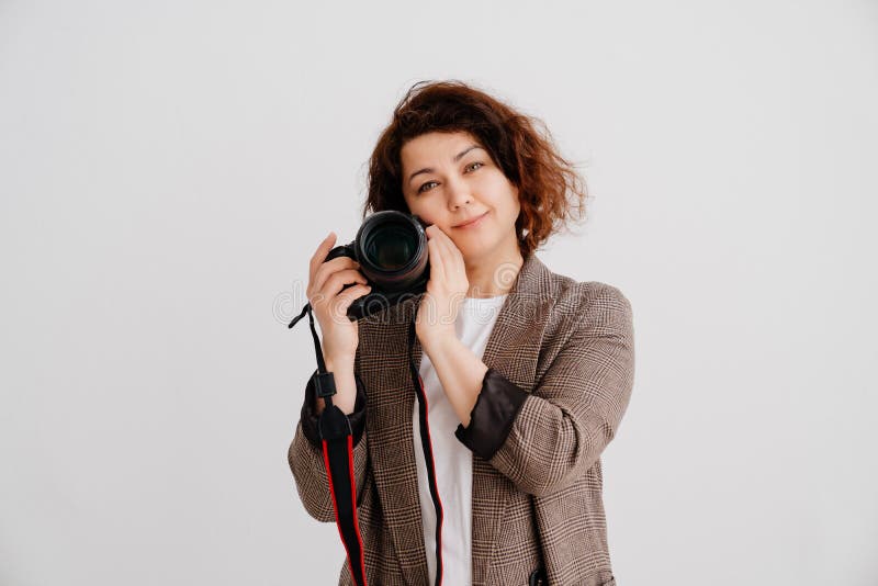 brunette woman in T-shirt and checkered jacket on a white background with camera