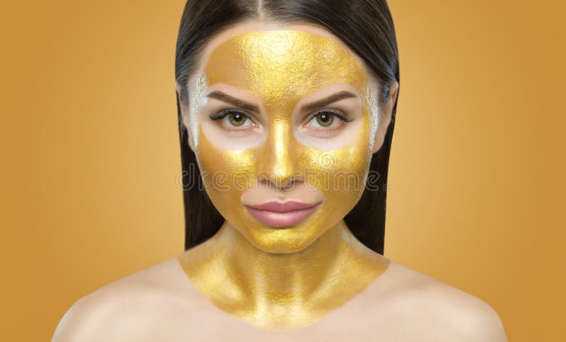 Portrait Of A Brunette Woman Who Makes A Golden Mask On Her Face Neck And Collarbones Against