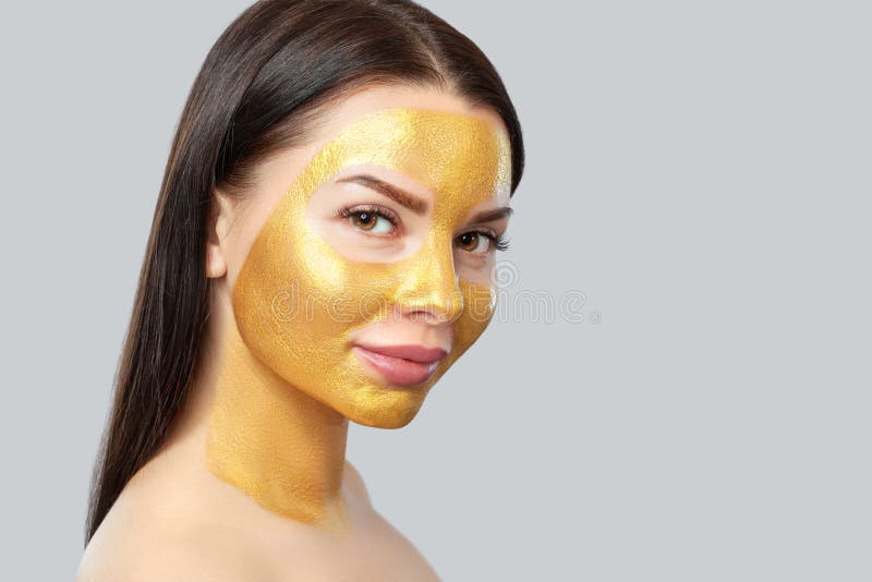 Portrait Of A Brunette Woman Who Makes A Golden Mask On Her Face Neck And Collarbones Against