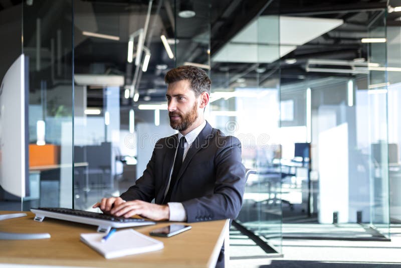 Portrait of businessman with beard, happy man working in office successful boss working at computer in modern office stock photos