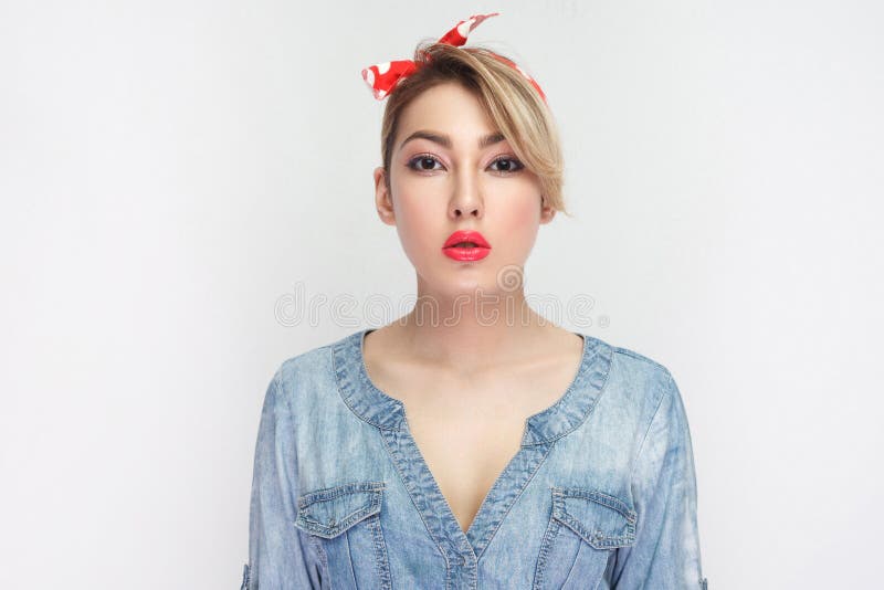 Portrait of calm serious beautiful young woman in casual blue denim shirt with makeup and red lips and headband standing and stock photos Portrait of calm serious beautiful young woman in casual blue denim shirt with makeup and red lips and headband standing and stock photos