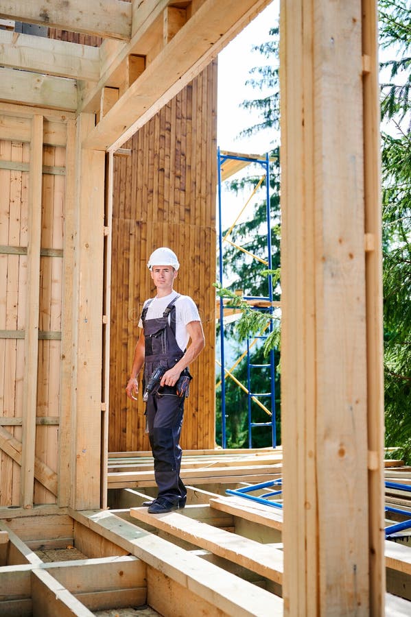 Carpenter Working with Screwdriver while Constructing Wooden Framed House. Stock Photo Image