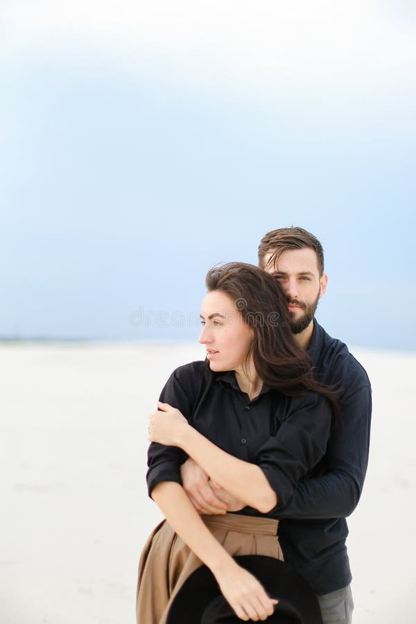 Portrait of caucasain man hugging woman in monophonic background.