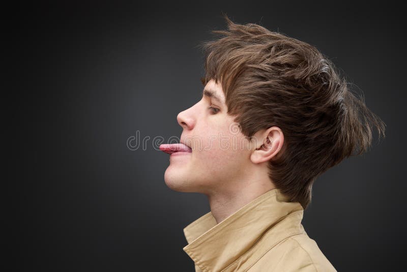 Profile side view portrait of attractive funny boy showing tongue