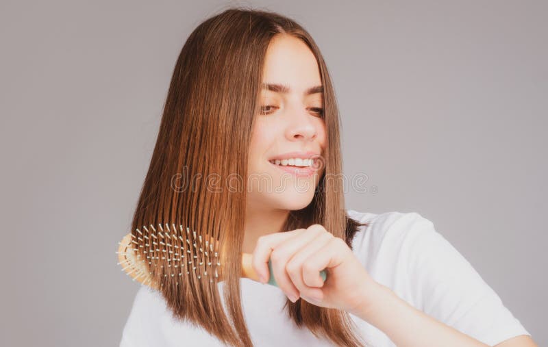 Portrait of charming brunette hair lady combing hair with hairbrush comb, isolated. Young beautiful woman brush long