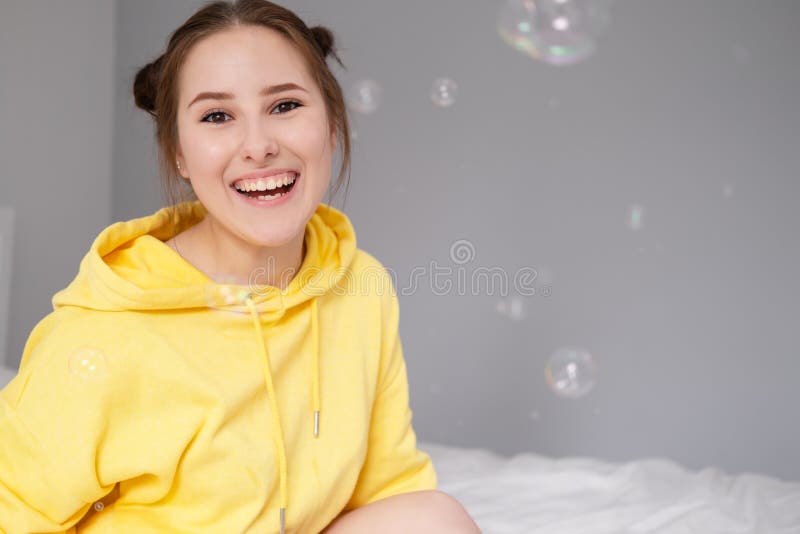 Portrait of charming young woman in yellow among soap bubbles on bright grey background. fashionable teenager. trendy stock photo