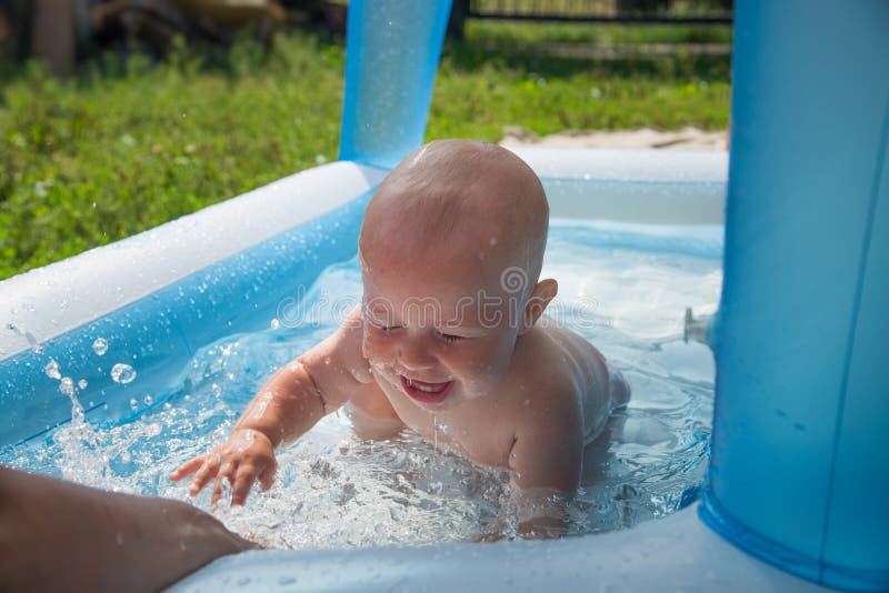 Portrait of cheerful baby boy playing in inflatable swimming pool