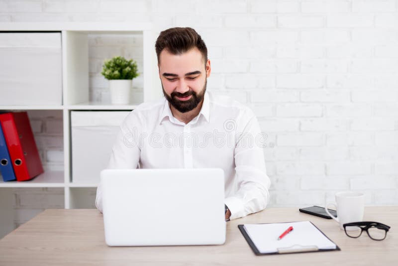 Portrait of cheerful bearded businessman using laptop in office stock photo Portrait of cheerful bearded businessman using laptop in office stock photo