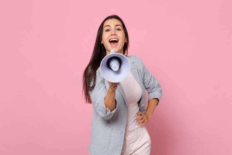 Portrait of cheerful beautiful funny young woman in striped jacket scream in megaphone isolated on pink pastel wall