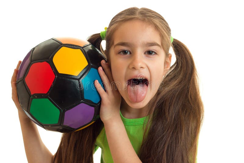 Portrait of a cheerful girl with a soccer ball shows tonque