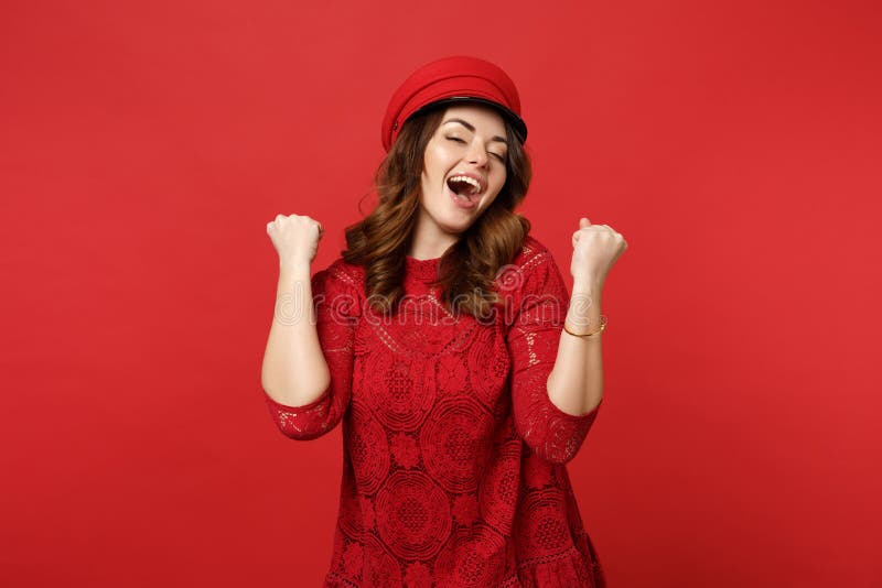 Portrait of cheerful happy young woman in lace dress, cap clenching fists like winner isolated on bright red wall royalty free stock images Portrait of cheerful happy young woman in lace dress, cap clenching fists like winner isolated on bright red wall royalty free stock images