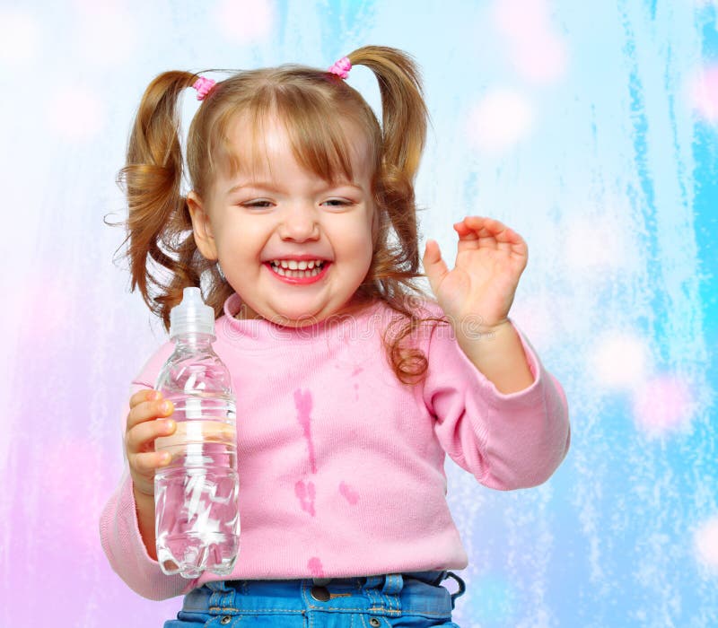 Portrait of a cheerful little girl drinking water from a bottle