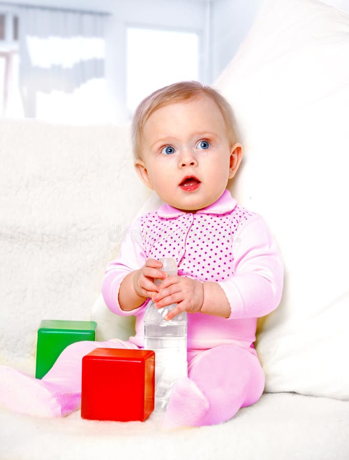 Portrait of a cheerful little girl drinking water from a bottle